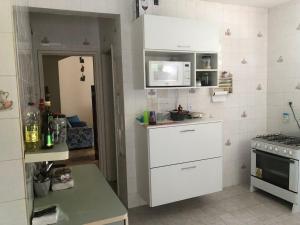 cocina pequeña con armarios blancos y fogones en Casa Lyrio - Itacimirim, en Camassari