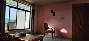 a room with a chair and a table and a window at Mezbaan Guest House in Nathia Gali