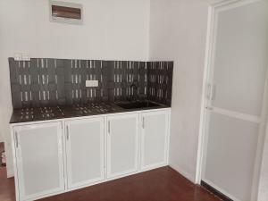 a kitchen with white cabinets and a sink at Senu's place in Matara