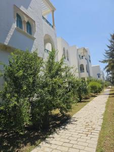 a building with trees next to a brick sidewalk at Chic Apartment Near the Sea in Yasmine