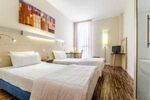 una camera d'albergo con due letti e un tavolo di Hotel YIT Ciudad De Zaragoza a Saragozza