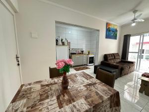 a living room with a table with a vase of flowers on it at Praia da Mirim - Apto a 100m do Mar in Samaritá