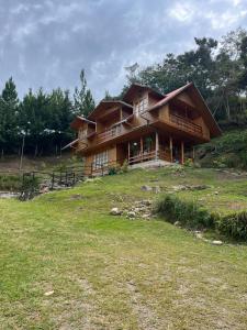a large wooden house on a hill with a field at La Arboleda Oxapampa in Oxapampa