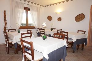 ein Esszimmer mit weißen Tischen und Holzstühlen in der Unterkunft Hotel Il Platano in San Teodoro