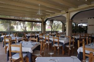 un comedor con mesas y sillas blancas en Hotel Il Platano, en San Teodoro