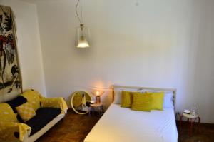 a bedroom with a white bed with yellow pillows and a couch at LIBERA IDEA Art run space in Civitanova Alta