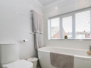 a white bathroom with a tub and a toilet and a window at Christlow Cottage in Bridlington +16 photos