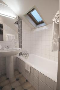 a white bathroom with a sink and a bath tub at Hôtel Noir in Paris
