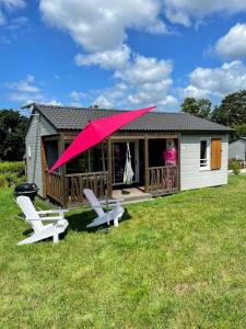 a house with a large pink umbrella in front of it at Chalet familial avec piscine-Finistère Sud in Pont-lʼAbbé