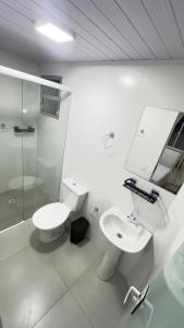 a white bathroom with a toilet and a sink at Casa espaçosa - Luar da Guarda in Palhoça +8 photos