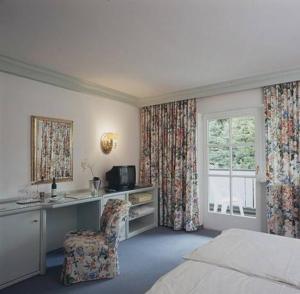 a bedroom with a bed and a desk and a chair at Hotel Seehof in Loibichl