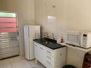 a kitchen with a sink and a microwave and a refrigerator at Flat Thermas Olimpia - 300 metros do Thermas dos Laranjais in Olímpia