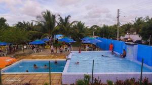 a group of people in a swimming pool with umbrellas at O Cantinho da Patricia e Tony in Macaíba