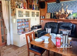 a living room with a wooden table and leather chairs at Littleholme in Potter Heigham