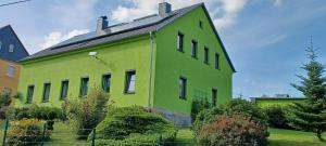 a lime green building with a black roof at Ferienwohnung Schiekel in Sebnitz