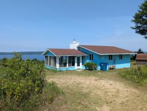 a blue house with a lighthouse on a beach at New! Hill Hideaway - Incredible Lakeviews! in Frankfort