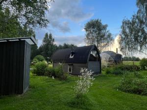 an old barn in a yard with a field at CEPĻI Glempings in Dunte +28 photos