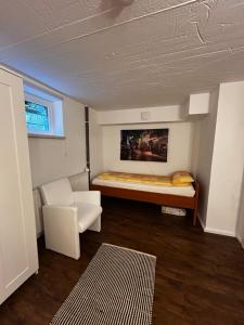 a small room with a bed and a white chair at Ferienwohnung Souterrain im stielvollen Landhaus bei Hamburg in Rosengarten
