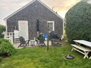 a picnic table and chairs on a deck with a house at Charming Beachside Bungalow in Truro +7 photos