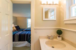 a bathroom with a sink and a bedroom with a bed at Charming Beachside Bungalow in Truro