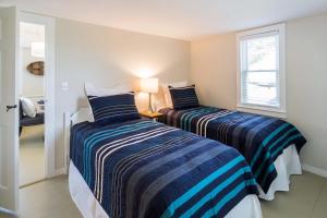 two beds in a small room with a window at Charming Beachside Bungalow in Truro
