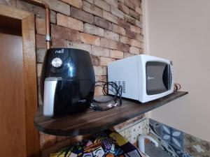 a microwave and a printer on a wooden shelf at Lindo flat Sabará Estilo Europa Vila Rica Pampulha in Venda Nova +11 photos
