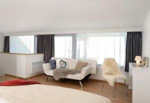 a white room with a couch and a chair at Apartmány Eden - Rezidence in Luhačovice