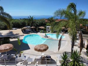 a view of a swimming pool with palm trees and chairs at Costa Real - Garden Retreat with Private beach, Pet Friendly in Capo Vaticano