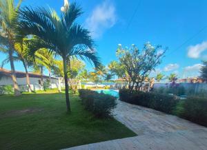 a palm tree in a yard with a swimming pool at Pousada Chalanas Flats in Canguaretama