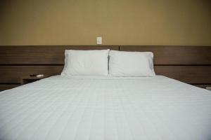 a large white bed with two pillows on it at Decio Hotel - Presidente Venceslau Antigo KHotel in Presidente Venceslau