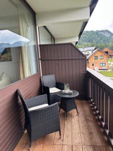 a patio with two chairs and a table on a balcony at Steinbock Apartement in Bad Goisern