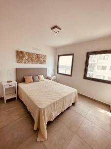 a bedroom with a large bed and two windows at Departamento de lujo con vista al mar in Monte Hermoso