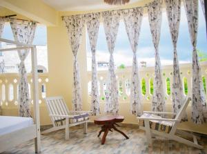 a bedroom with two chairs and a window with curtains at Peace and passion in Ukunda