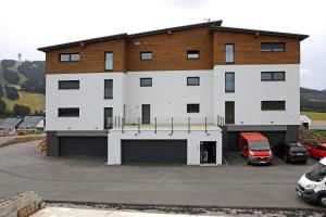 a large white building with a parking lot at Apartmány Horizont in Loučná pod Klínovcem