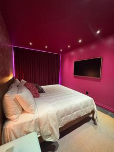 a bedroom with purple walls and a bed with a tv at Hotel Hilo - Room 203 in Louisville +17 photos