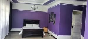 a bedroom with purple walls and a bed at WATO Villas in Bulindo +21 photos