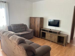 a living room with a couch and a flat screen tv at Pousada Corais in Ubatuba