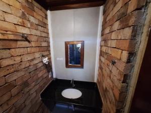 a bathroom with a white toilet in a brick wall at Lindo flat Serro Estilo Europeu Vila Rica Pampulha in Venda Nova +11 photos