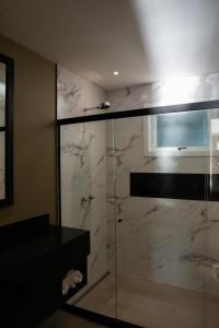 a bathroom with a shower with a glass door at Pousada Papiro Boutique in Abraão