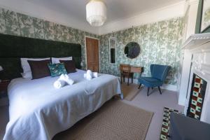 a bedroom with a large white bed with a blue chair at Hopewell - Unique Rooms in the heart of Cliftonville in Margate