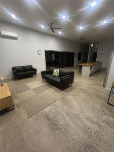 a living room with two black couches and a table at Birdys Retreat in Rarotonga