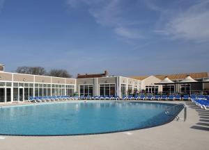 Una gran piscina con sillas azules y un edificio. en Megerlilly Haven, en Pagham