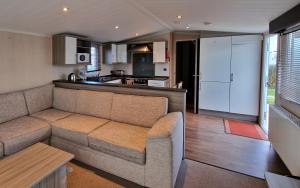 Una sala de estar con un sofá y una cocina. en Megerlilly Haven, en Pagham
