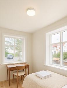 a bedroom with a bed and a desk and two windows at Downtown Boutique Apartment in Akureyri