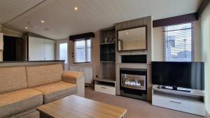 a living room with a couch and a flat screen tv at Megerlilly Family Hideaway, Church Farm in Pagham +2 photos