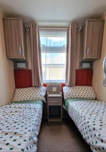two beds in a small room with a window at Megerlilly Family Hideaway, Church Farm in Pagham