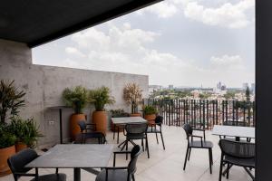 a patio with tables and chairs and a view of the city at Lapso At Asís in Guadalajara
