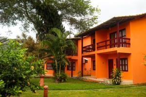 an orange building with a palm tree in front of it at Pousada é in Cumuruxatiba