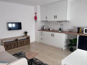 a kitchen with white cabinets and a tv on the wall at Alojamento Campo Maior in Campo Maior