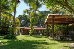 a house with a pavilion in a yard with palm trees at Pousada Villa Cumuru in Cumuruxatiba